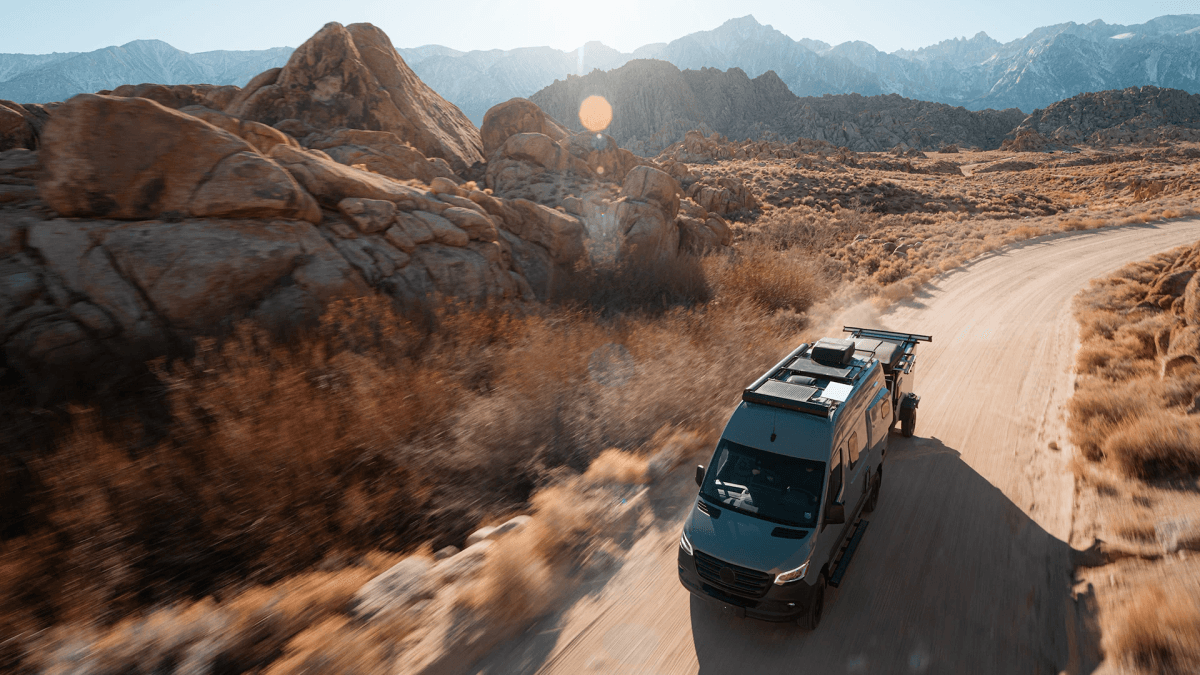 Camper van traveling through mountains with Starlink equipment mounted on the roof
